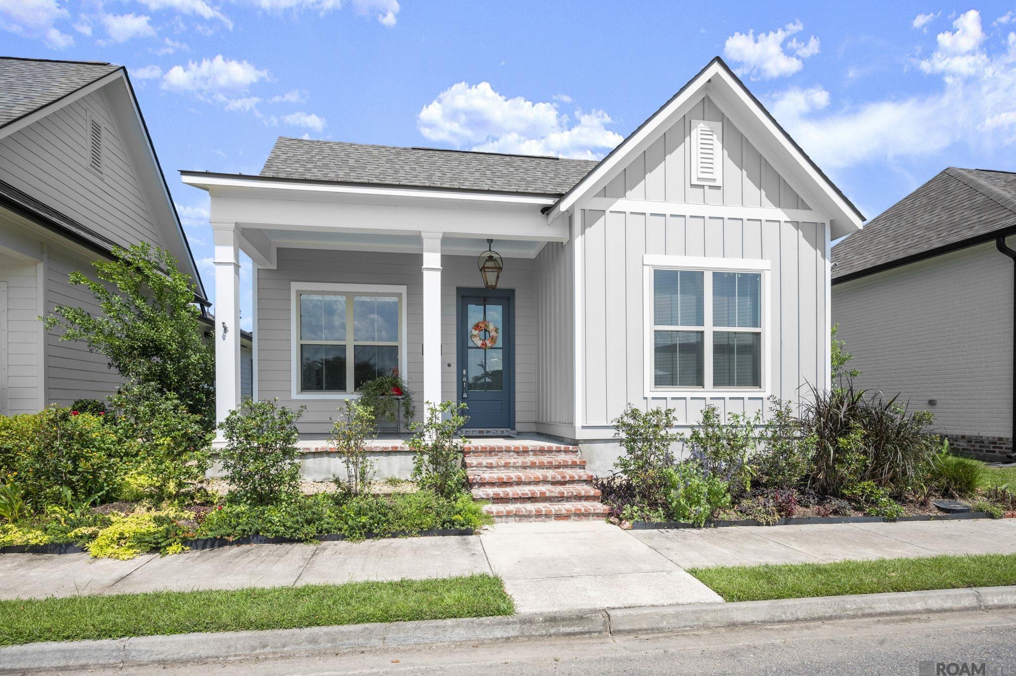 This quintessential New Orleans style cottage provides easy low-maintenance living. Completed in 2022 and still like new construction. Relax on your covered  front porch that has a metal overhang and walk into the open living area, kitchen and dining which are separated by exposed cypress beams which will have a "Dark Oak" finish. The gourmet kitchen features custom painted cabinets with 5" hardware pulls and under cabinet lighting, large center island with stainless granite composite sink and overhanging pendant lights, 3 cm Moonlite granite, White Bright Ice subway tile backsplash, stainless appliance package including a gas cooktop, built in wall oven and microwave and a walk in corner pantry. Beds two and three are located at the front of the home and the master suite is located off of the rear of the home for peace and quiet! The master bedroom features a spa like bath with a separate soaking tub, custom tiled shower with seamless glass enclosure, dual vanities, linen closet and walk in closet. Courtyard patio is located off of the kitchen and plumbed for gas grill. The yard is professionally landscaped and fully sodded. The Village at Conway is a "walkable" TND (Traditional Neighborhood Development featuring walking trails, parks, lakes with clubhouse & pool, Community Amphitheater, restaurants, shops & much more!  15-20 mins from Baton Rouge & 50 mins from New Orleans; just 2 minutes to the I-10 Burnside Exit; with shops, restaurants and a grocery store just miuntes from your doors step.