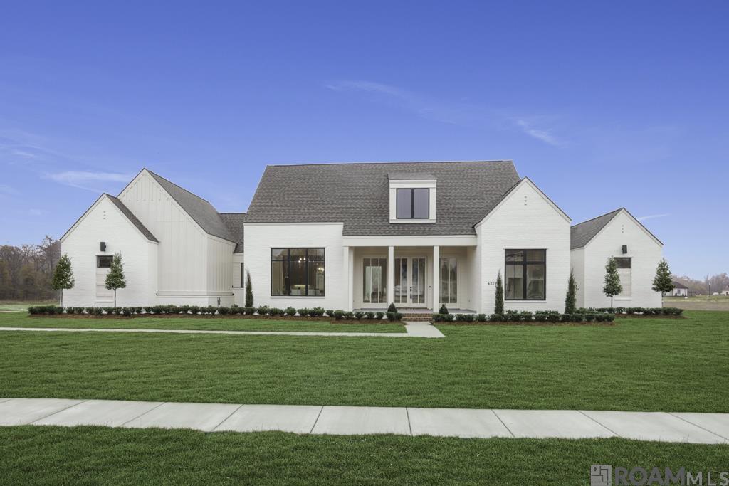 Another stunning collab from architect Dwayne Carruth & builder Carl Crawford. This home meshes thoughtful custom design sensibility and exceptional craftsmanship. A Modern Farmhouse concept that looks, feels, and lives like a true custom designed home. Set on a gorgeous 1.34-acre lot, offering both space and serenity with a beautiful lake view and plenty of room for a pool. The thoughtfully designed 4BR/3BA triple-split floor plan, is a spacious 2755 sq ft of functional luxury. The unique primary suite joins an impressive bath featuring hardwood floors, custom tile shower, and freestanding tub set against a dramatic tile feature wall. Double vanities and a huge primary closet are the finishing touches to this amazing space. A guest suite located to the front with two more bedrooms tucked in the rear allow privacy for all. The open-concept kitchen and living area create the heart of the home, with beautiful views, a dramatic fireplace wall and a stunning center island. Offset dining also allows for more formal gatherings. High-end finishes found throughout: custom cabinets, hardwood floors, quartz countertops, stainless appliances, butler’s pantry, and a laundry room as beautiful as it is functional. Every detail—from designer lighting to window placement were selected to maximize function and beauty, with lake views from nearly every room. Outdoors is just as impressive, with it's huge back porch, built-in grand fireplace and outdoor kitchen. Perfect for relaxing or entertaining. Out front, a welcoming and dramatic entry with double french doors and floor to ceiling windows. The double-car garage includes a generous storage area. Pretty-as-a-picture landscaping, features decorative trees and carefully selected elements, making it one of the most striking homes in Hidden Lakes. The perfect balance of rural living and convenience, just a short drive to shopping, restaurants, medical care, entertainment, and top-rated schools make this an ideal place to call home.