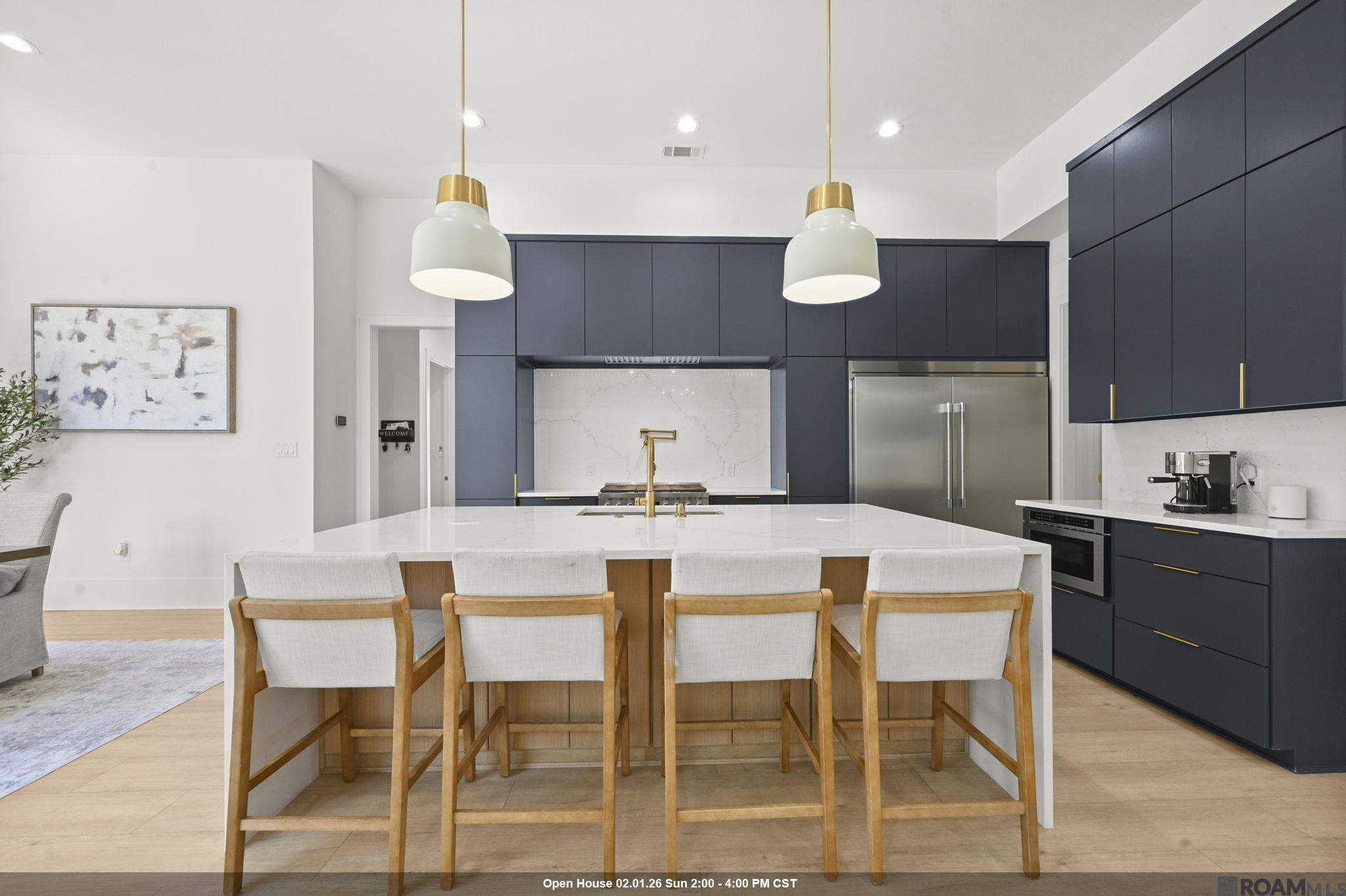 Open House - Sunday, February 1st - 2-4pm! Located in the desirable Hidden Lakes community of Prairieville, this stunning one-year-old custom home sits on a spacious 1.37-acre lot with a fully fenced backyard. Designed with comfort and function in mind, the home offers 5 bedrooms and 4.5 baths, with 4 bedrooms and 3.5 baths located on the first floor (2,698 sq ft). 2nd floor has full bedroom, attached bathroom, large walk in closet and walk in attic access.   The home features an open floor plan with a gourmet kitchen showcasing quartz countertops, a waterfall-edge island with two pop-up outlets and a flat phone charging station, and a built-in stainless steel refrigerator. A custom walk-in pantry includes built-in drawers and shelving, providing ample storage space.  One guest bedroom downstairs has its own private en-suite bath, while two others share a Jack and Jill bathroom. All bathrooms are outfitted with custom tile flooring, quartz countertops, tiled tub surrounds, and sleek electronic light-up mirrors. The luxurious primary suite offers peaceful views of the backyard, a spa-like bathroom with dual floating vanities, a large wet area with walk-in shower and freestanding tub, and a spacious walk-in closet with room for a vanity. The adjoining laundry room includes storage cabinets, a sink, and quartz counters.  Unique touches throughout the home include a hidden dog room tucked under the stairs, complete with custom doors—perfect for your furry family member. A mudroom is conveniently located off the 3-car garage, ideal for everyday storage and organization.  The outdoor living space features a covered patio with a full outdoor kitchen, plus a separate powder room with access from the backyard. With plenty of room to add a pool, barn, or guest house, this property offers the perfect blend of luxury, functionality, and room to grow. Home does not require flood insurance!