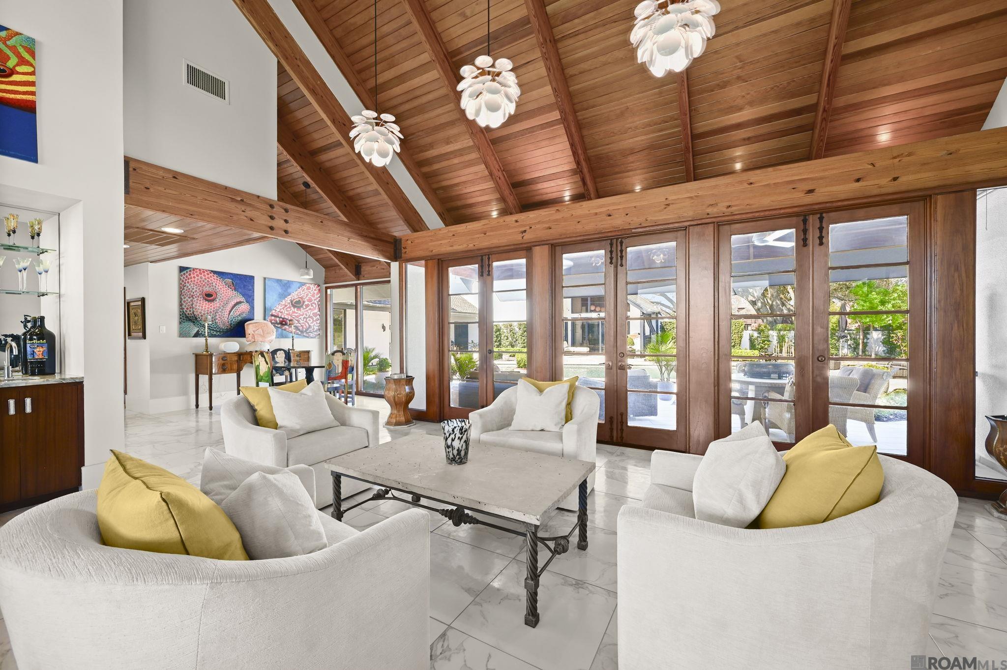 Experience the pinnacle of luxury in this stunning Mid-Century Modern inspired estate, perfectly positioned on a premier lot overlooking the prestigious Baton Rouge Country Club golf course. Completely renovated in 2018, this architectural masterpiece seamlessly blends high-end design with superior craftsmanship, showcasing Canadian tongue-and-groove wood ceilings, soaring vaulted ceilings with varied heights, and solid wood doors throughout the home. Designed for both grand entertaining and everyday living, the expansive open-concept layout offers multiple living areas that feel bright, airy, and effortlessly connected to the outdoors. Large windows frame breathtaking views of the golf course and pool, while three sets of French doors open to a private backyard oasis. Entertain with ease in the stylish living spaces featuring a dedicated bar area complete with two wine refrigerators and two ice makers, creating the perfect setup for hosting. The ultra-modern chef’s kitchen is equipped with a 48” Monogram six-burner gas range, sleek full-overlay cabinetry, a seamlessly integrated refrigerator, stainless steel appliances, two dishwashers, and exceptional functionality for everyday living and entertaining.  The main residence offers 3 bedrooms and 3.5 bathrooms, complemented by a detached poolside guest suite with a full bath—ideal for a home office, gym, guest quarters, or recreation space. Outdoors, enjoy true resort-style living. The courtyard features a custom gunite pool with a lounging area, a built-in Blaze grill, and a spacious covered patio. The property also offers two fire pits—one located poolside for cozy evenings by the water and another perfectly positioned in the rear yard for enjoying sunset views over the golf course. Additional highlights include a two-car garage with epoxy flooring and dedicated golf cart storage. Ideally located just minutes from Towne Center, Mid City, and convenient access to Interstate 10 and Interstate 12.