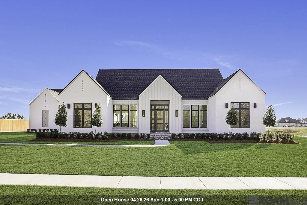 Situated on a premier one-acre waterfront lot in peaceful Hidden Lakes, this brand new construction offers a perfect blend of modern luxury and architectural sophistication with a stunning cool color palette that is timeless and beautiful. This home features a spacious 4BR/3BA triple split floor plan with high-end custom finishes and a seamless open-concept layout. The primary suite is functional, quiet luxury with the oversized walk in closet, gorgeous, fully tiled walk-in shower, freestanding tub set against a beautiful tile accent wall, and double vanities. The home has two additional bedrooms with a bath and a separate, private guest room and bath. The entry is stunning with the checkerboard marble tile floor leading into the main living space, that boasts white oak hardwood floors and a bold brick fireplace and cypress mantle. The kitchen features an impressive, oversized quartz island that calls you to sit and stay a while. Entertaining is a breeze with the large dining area, island bar, oversize outdoor patio and scullery kitchen offering effortless organization and prep, with the additional sink, counterspace and storage galore. Living here just gets better. Enjoy the serene water view from the knockout covered porch, complete with gas grill, sink and fridge, perfect for enjoying the outdoor space. Relax on the quiet front porch while enjoying your morning cup of coffee. All this functional luxury plus a spacious laundry room, two car garage, large storage area and a practical drop zone. Nestled within the top-rated Ascension Parish School System, this signature property provides a rare opportunity for private, upscale living in one of Prairieville’s most desirable areas. Close to local amenities! Flood zone X!