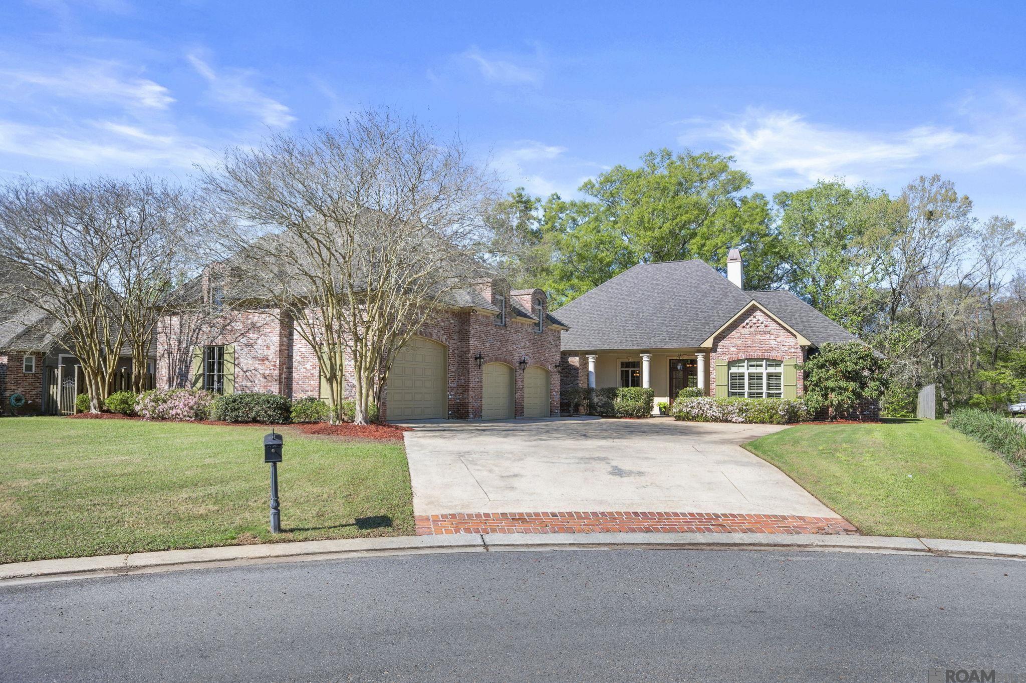 Custom-built home on 1.28 acres in the desirable Bluff Oaks subdivision in Prairieville, LA. This spacious residence offers 5 bedrooms and 4 full baths, along with an exceptional layout featuring a formal living room, keeping room, formal dining room, and a theater room with bar.  The home showcases Old Saint Louis brick, 12-foot ceilings, and beautiful smooth-finish pine wood floors (nail-down on sleepers). The gourmet kitchen is designed for both function and style with abundant custom cabinetry, a large island, beverage refrigerator, gas cooktop, Bosch dishwasher, microwave, and convection wall oven.  The living room features a wood-burning fireplace with custom built-ins. The primary suite, located on the first floor, overlooks the expansive backyard and includes a luxurious bath with dual vanities, quartzite countertops, a large walk-in shower, self-drying soaking tub, and an oversized walk-in closet.  Also located on the first floor are two guest bedrooms, each with access to a full guest bathroom, providing comfortable accommodations for family or visitors.  Upstairs includes two additional bedrooms and a full bath, along with a theater room featuring a wet bar, sink, cabinetry, and refrigerator.  Outdoor living is equally impressive with a brick-arched patio overlooking the acreage, plus a brick outdoor kitchen and wood-burning fireplace, perfect for entertaining.  Additional features include a new roof (2025) and exceptional garage and storage space. The extra-long two-car garage accommodates larger vehicles, while the attached second garage (approximately 620 sq ft) offers enough height to store a boat. A separate 354 sq ft storage/workshop area with an additional roll-up garage door provides excellent space for hobbies or projects.  This immaculate property is conveniently located off Bluff Road with easy access to top-rated schools, shopping, and Baton Rouge.