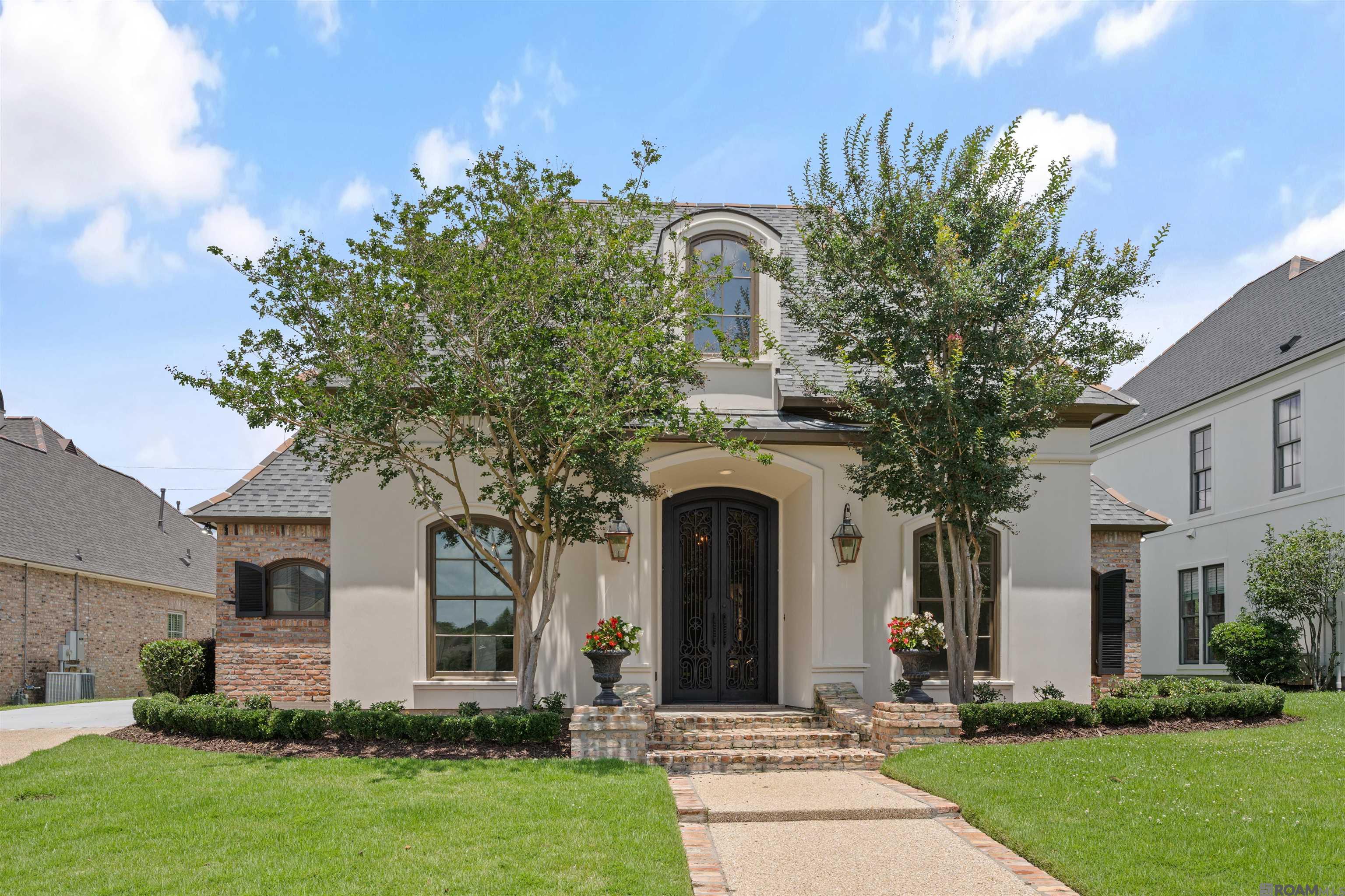 Nestled in the heart of Baton Rouge within prestigious GATED Bocage Lake, this extraordinary luxury estate offers modern updated finishes and is completely move-in ready.  Featuring 5 bedrooms, 3.5 baths, multiple living areas, & a private GUEST/MOTHER-IN-LAW SUITE, this home is ideal for multi-generational living, entertaining & everyday comfort. Inside, soaring 12-foot ceilings, triple crown molding, chandeliers, canned lighting, refinished wood floors, & custom details create timeless elegance throughout. The spacious family room features built-in bookcases & entertainment center, fireplace, & adjoining sunroom filled with natural light. The chef’s kitchen includes Taj Mahal quartzite counters, decorative backsplash, stainless appliances, 4-burner gas cooktop, wall oven, walk-in pantry, breakfast bar seating, breakfast room, & a brand-new stainless refrigerator/freezer. The luxurious primary suite features wood flooring, dual walk-in closets & a completely rebuilt spa-inspired bath with split vanities, soaking tub, & custom glass shower. The hallway bath has also been fully renovated. Three additional bedrooms are spacious with wood flooring, while the fifth bedroom & oversized 25x20 SECOND LIVING ROOM room create the perfect private living quarters complete with full bath, laundry area & kitchen. Extensively updated, improvements include freshly painted interior/exterior, refinished wood floors & doors, updated HVAC system, new thermostats, serviced A/C systems, enhanced landscaping, rebuilt front entrance brickwork, & a NEW ARCHITECTURAL ROOF replaced 1.5 years ago offering peace of mind plus tremendous value. Outdoor amenities include a charming courtyard with privacy for each home, covered entertaining area, outdoor kitchen, wood-burning fireplace, & gas lanterns. BONUS - the garage is fully air conditioned! A rare opportunity to own a meticulously updated luxury home in one of BR’s most sought-after communities with endless potential!