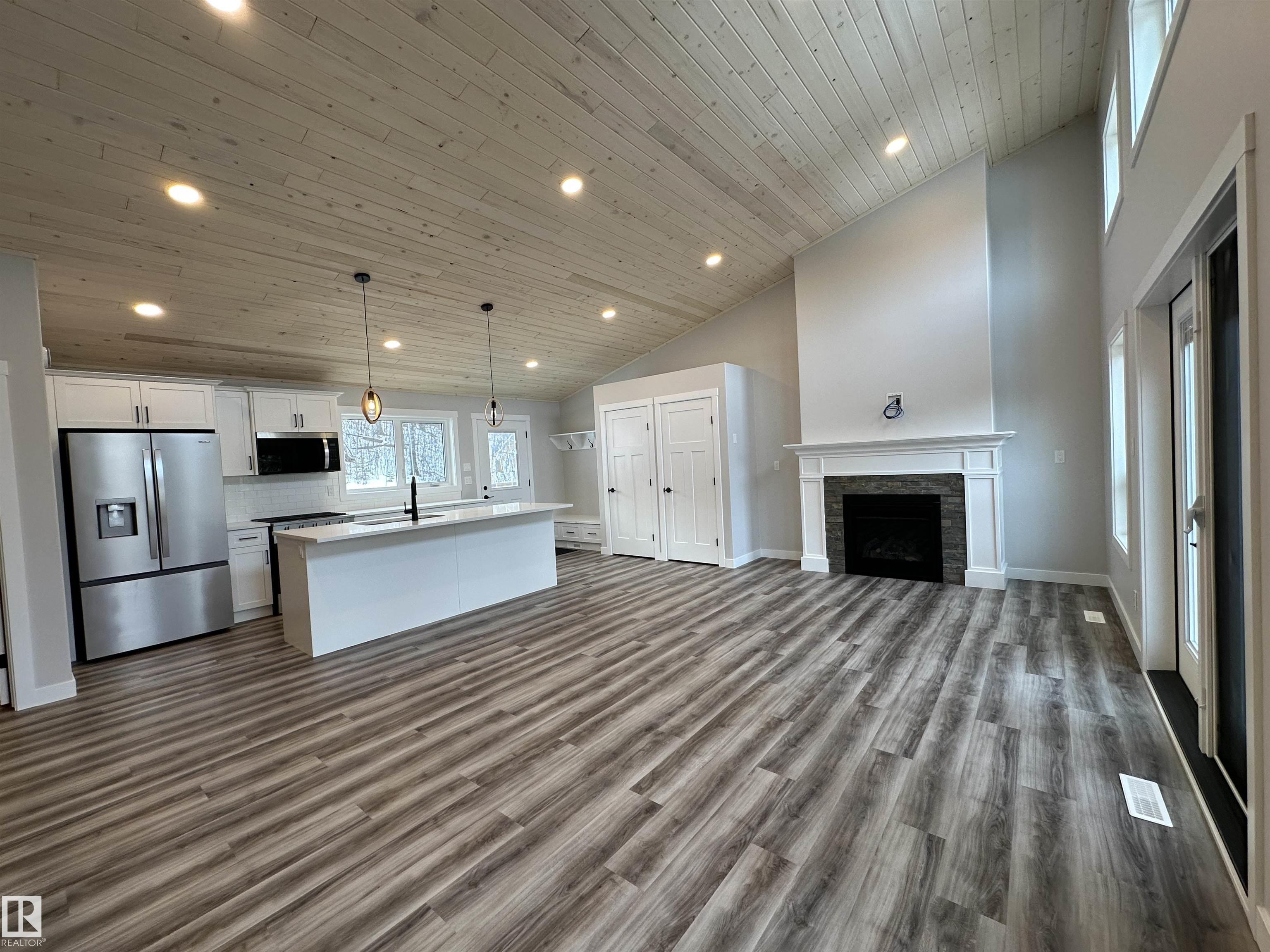 W O W THIS PROPERTY IS AMAZING!  Wide open design, soaring 14' vaulted ceilings throughout the entire main fl, big windows w loads of natural light, 8' quartz topped peninsula island, shaker style kitchen cabinets, 4 piece stainless steel appliance pkg w/ gas range, walk in pantry, luxury vinyl plank flooring, fireplace, 2 bedrooms up and 4 piece main bath. Stepping out of the vaulted great room, you're immersed in the peaceful sights and sounds of nature off your huge wrap around deck. The kitchen open to your private oasis and rear yard deck. The finished walkout basement has in-floor heat, 9' ceilings, primary suite w/ a 4 piece ensuite, laundry/utility rm w/ washer/dryer, 21x24 drywalled, taped and painted garage. 100 AMP power service, drilled well and a 2800 gallon septic holding tank. Tucked on a private, pie shaped lot surrounded by mature trees. Close to the shores of Isle Lake, the beach, boat launch and only 45 min west of Edmonton. Price includes GST, with rebate assigned back to the builder.