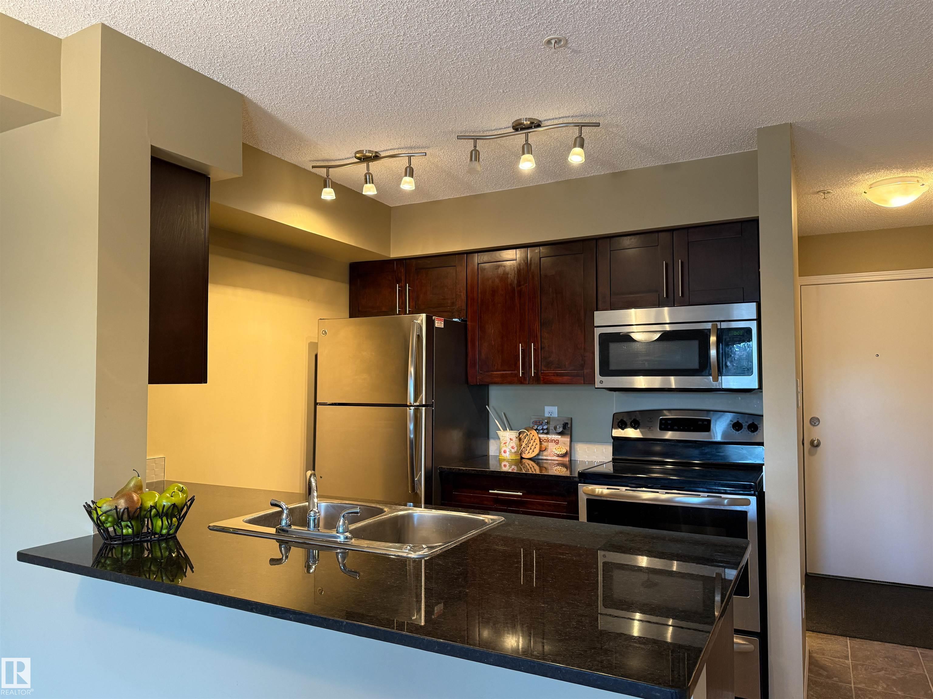 Charming 2-Bedroom Condo in McConachie. Discover this bright and modern 2-bedroom, west-facing condo located in the quiet, family-friendly community of McConachie in Northeast Edmonton. Ideally situated close to schools, parks, shopping, and public transit, this home offers the perfect balance of comfort and convenience?ideal for first-time buyers, downsizers, or savvy investors. The open-concept layout features granite countertops, stainless steel appliances, and in-suite laundry, making everyday living both stylish and functional. Large west-facing windows flood the space with natural light, creating a warm and welcoming atmosphere throughout the year. Step outside onto the generously sized deck and enjoy beautiful summer sunsets. Additional highlights include an energized parking stall and quick access to major commuter routes and local amenities, all while enjoying the peace of a well-established residential neighbourhood.