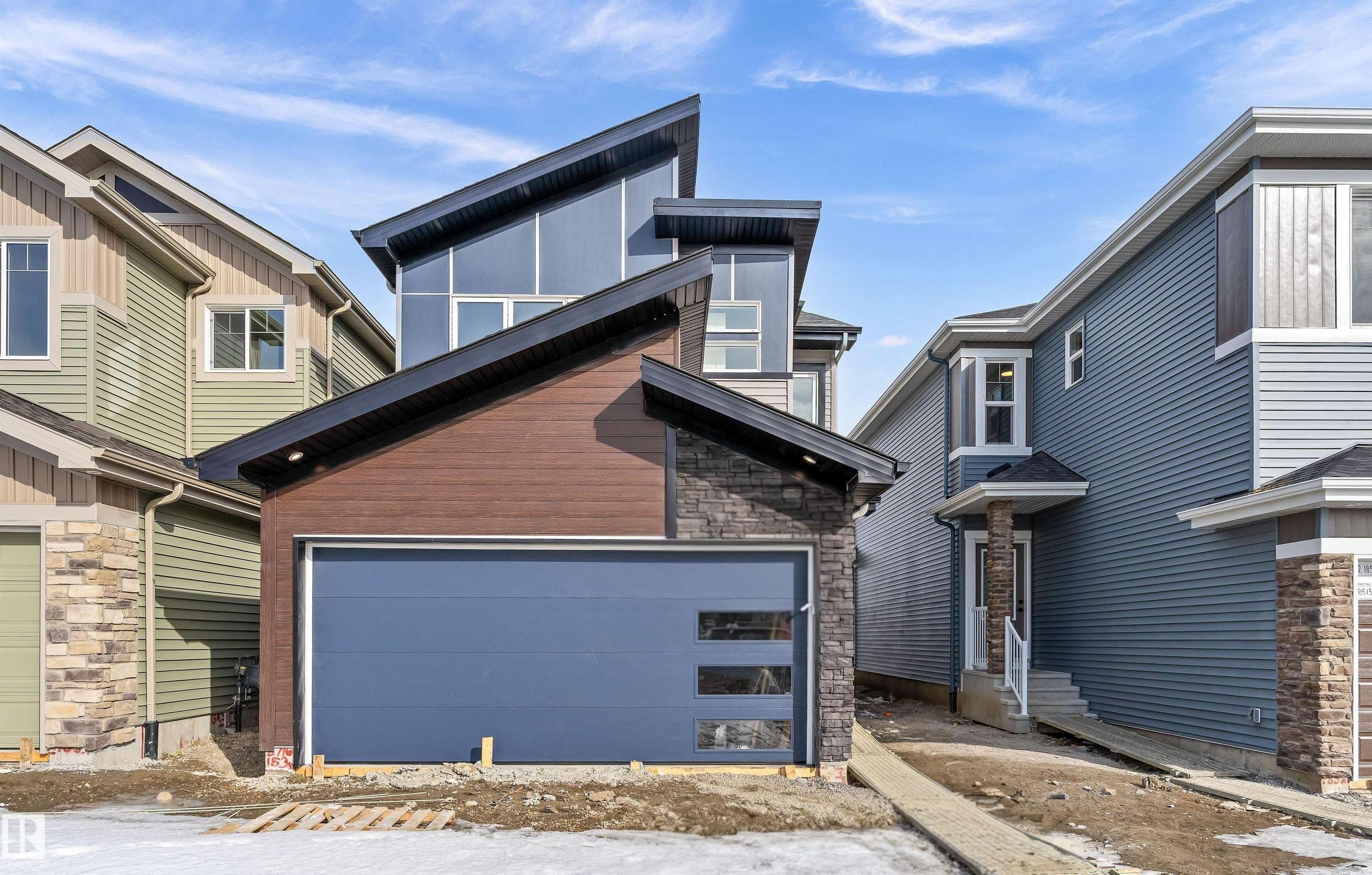 Built by Sterling Homes, this front-attached home in College Woods at Lakeview offers bright, modern living near trails, greenspace, and natural calm. Triple-pane windows and 9? ceilings fill the open-concept main floor with light, from the foyer to the spacious great room with electric fireplace. The kitchen features quartz countertops, a large island, ceiling-height cabinetry with crown moulding, chimney hood fan, built-in microwave, and corner pantry?ideal for daily living and entertaining. A garden door opens to the backyard with a convenient half bath on the main level. Upstairs, the primary suite includes a walk-in closet and 4-piece ensuite with double sinks and glass shower. A central bonus room, upper laundry, full bath, and two bedrooms complete the layout. Finished with luxury vinyl plank flooring, upgraded railings, side entrance, double attached garage with floor drain, and basement rough-ins, this home offers comfort in a peaceful, nature-inspired community.
