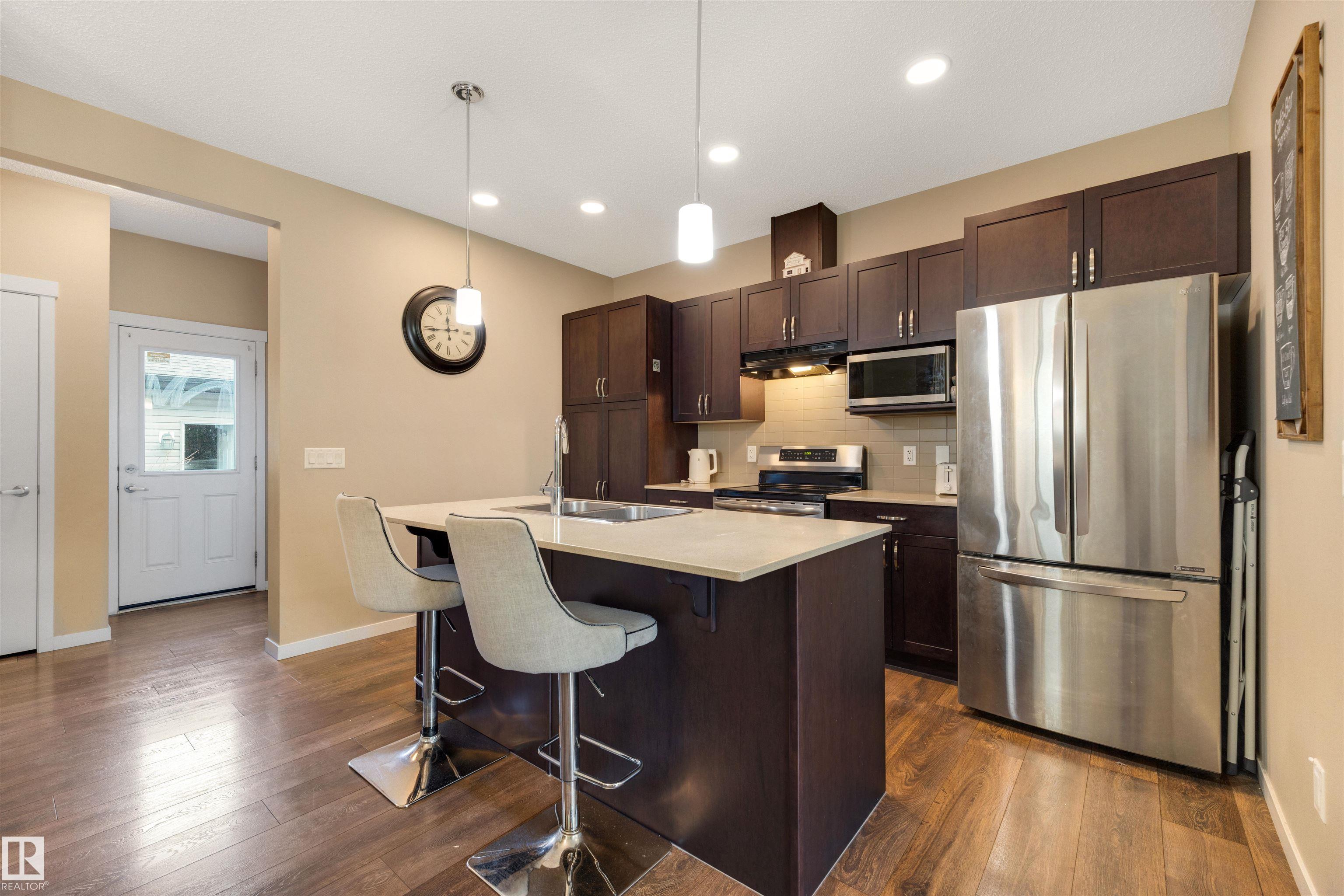 Welcome to this stunning end-unit Sterling Homes 2-storey in the heart of Tamarack, one of Southeast Edmonton’s most walkable communities with no condo fees. Offering 1,435sqft, 4 bedrooms, and 3.5 bathrooms, this home features a bright open-concept main floor with 9 ft ceilings and large windows, a kitchen finished with quartz countertops, tiled backsplash, pantry, and an oversized island with eating bar flowing into the dining area, plus a convenient main floor half bath and laundry. Upstairs includes three generous bedrooms, including a king-sized primary suite with a walk-in closet and a 4-piece ensuite, along with an additional full bathroom. The basement adds a spacious family room, fourth bedroom, and 3-piece bathroom, while the fenced yard with deck and double detached garage completes the package. Located steps from schools, the Meadows Recreation Centre, library, parks, shopping, and transit, with quick access to major routes, this home offers exceptional convenience and an unbeatable lifestyle.