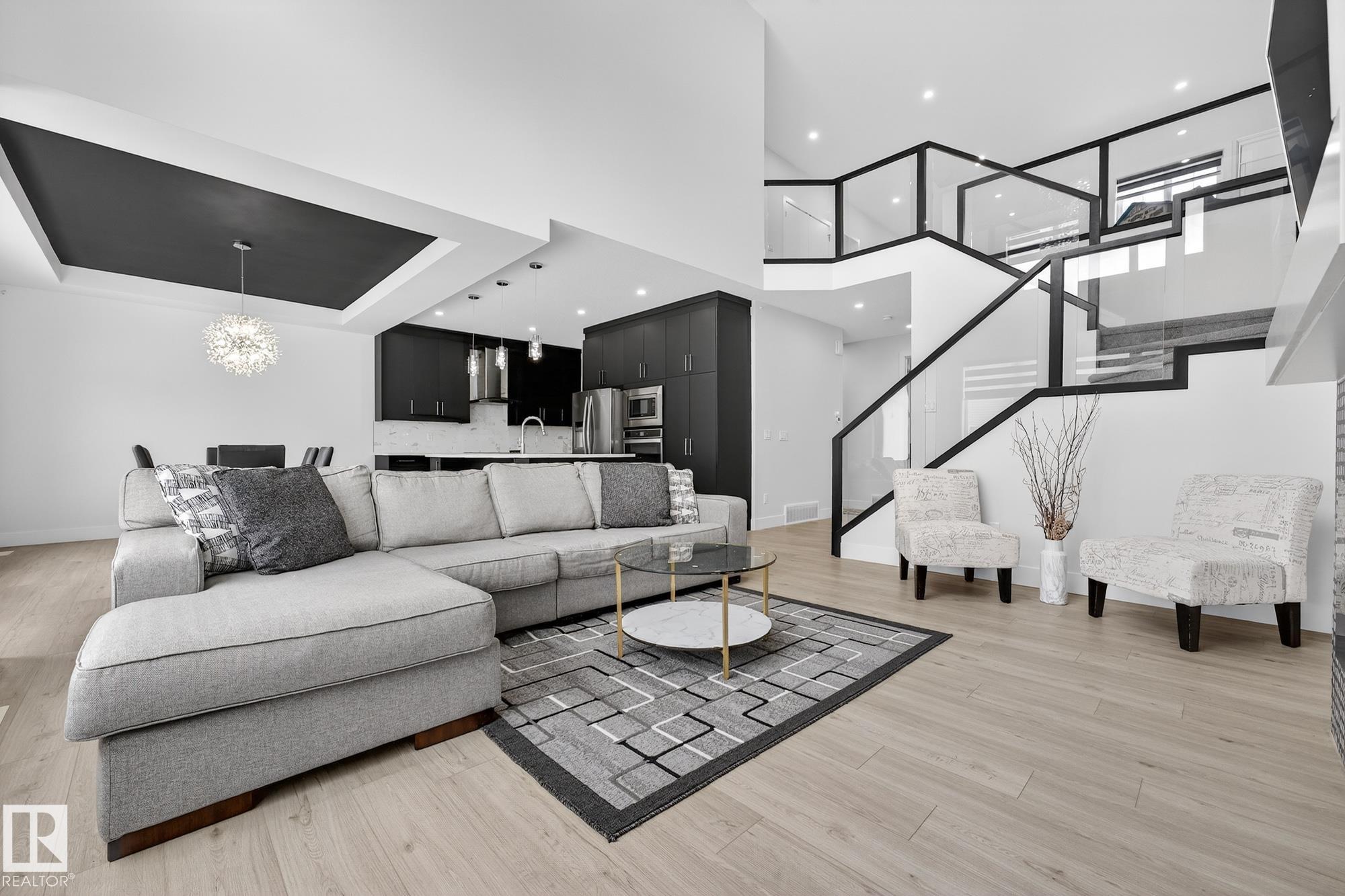 Sleek, modern and beautifully customized, this stunning home in sought-after Triomphe Estates offers luxury living on a pie-shaped lot tucked into a quiet cul-de-sac, just steps from walking trails and schools. The open-to-below main floor showcases soaring ceilings and expansive windows that flood the home with natural light. A versatile main floor office/den - ideal as a guest bedroom - is paired with a full bathroom for added flexibility. The designer kitchen features quartz countertops, matte black cabinetry, a butler's kitchen/walk-through pantry, and seamless flow into the spacious mudroom with access to the triple tandem garage. A convenient side entrance leads to the fully finished basement, complete with a fifth bedroom, theatre-style setup, and dedicated gym area. Upstairs offers two impressive primary suites, each with its own ensuite, plus two additional oversized bedrooms, a generous bonus room, and an upper-level laundry room. A rare blend of style, space, & function in one remarkable home!