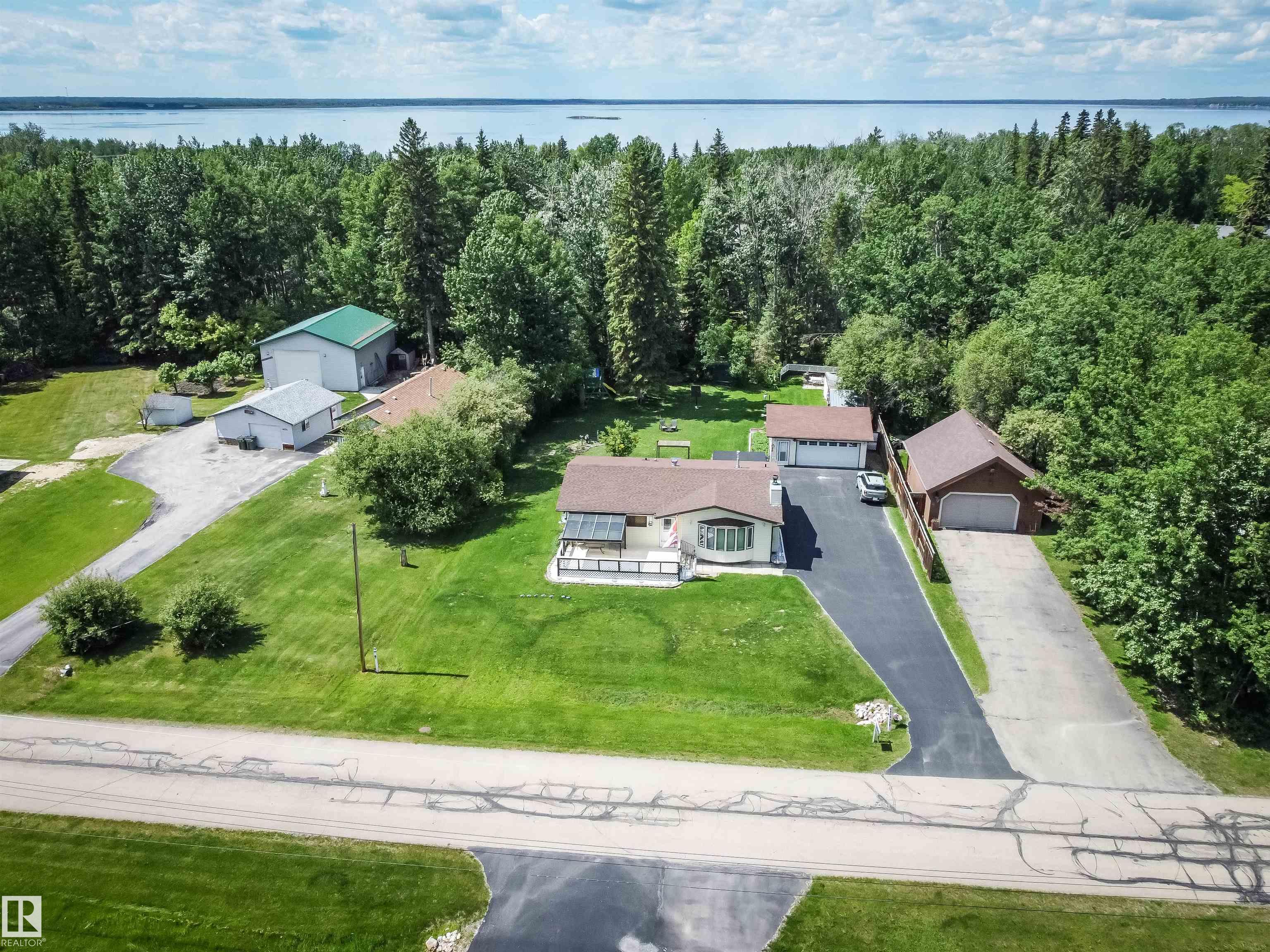 This Sunset Point home is a stunner!! 1260 sf bungalow set on a perfectly manicured half acre with paved driveway and  detached garage.  This home boast pride of ownership throughout with 3 bedrooms, 1 full bath, with jacuzzi tub, large kitchen and extra large living room with wood burning fireplace, dining area and kitchen plus a back covered in porch area, heated for  year round use.  Large deck off front with sun shelter or relax in the back deck with bbq area and watch the kids play in the play centre at the back.  Firepit area great for cool summer nights.  Situated close to golf and lake.  Enjoy year round living with country and recreational flair.  Air conditioning, garden (planted with potatoes and carrots for the new owners), and apple trees and rhubarb .  24x24 detached heated garage and tons of storage in the sheds.  Only 35 minutes NW of Edmonton.