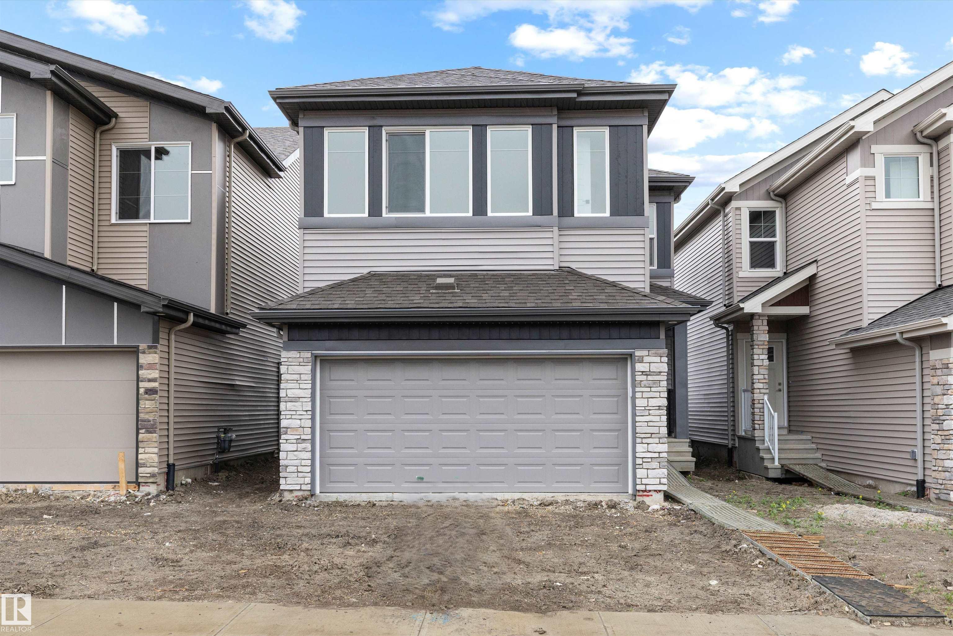 This well-designed home offers a balanced layout that blends function and everyday comfort. The main floor features 9' ceilings, LVP flooring throughout, a double attached garage with floor drain, and a separate side entrance. A welcoming foyer leads past a flexible den and convenient 2-pc bath into the bright, open kitchen, great room, and nook. The kitchen is equipped with quartz counters, an island with flush eating ledge, undermount sink, built-in microwave, chimney-style hood fan, full-height tile backsplash, soft-close raised-profile cabinetry, and a corner pantry. Large windows and a sliding patio door bring in natural light and provide backyard access. Upstairs includes a spacious primary with walk-in closet and 5-pc ensuite, plus a bonus room, two bedrooms, a full bath, and laundry. Black fixtures and basement rough-ins complete the home.