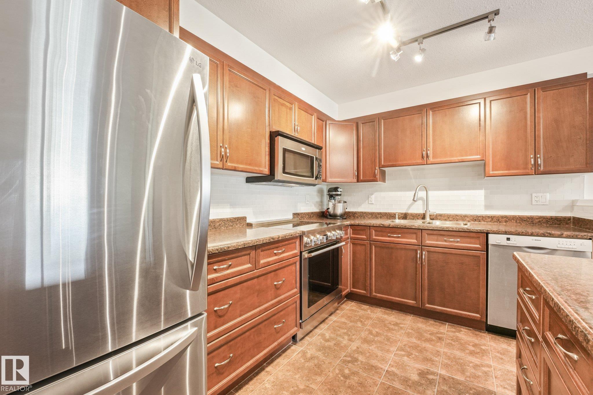 Welcome to Glastonbury Estates - a pet-friendly, adult community thoughtfully designed for mobility and accessibility. This meticulously maintained two-bedroom home offers a step-free entrance, wide doorways and hallways, an open-concept layout and a wheelchair-friendly bathroom. The kitchen features beautiful cabinetry, ample counter space, stainless steel appliances (including a brand-new induction stove), a tile backsplash and central island with seating. Large windows fill the inviting living room with natural light, while a striking stone feature wall adds warmth and character. The primary bedroom offers two closets and the ensuite has a spacious shower with grab bars & seat. Second bedroom is ideal for guests or a home office. Additional highlights include a brand new washer & dryer, central A/C, a gas BBQ hookup and heated underground parking with storage. Amenities include a guest suite, exercise room, social room and library. Close to shopping, dining, transit, Anthony Henday and Whitemud Drive.