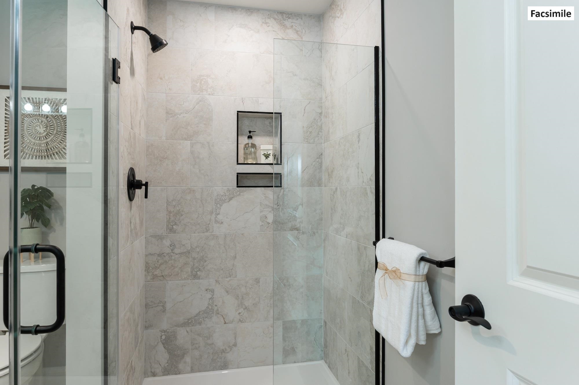 Tiled shower with glass door in primary bathroom