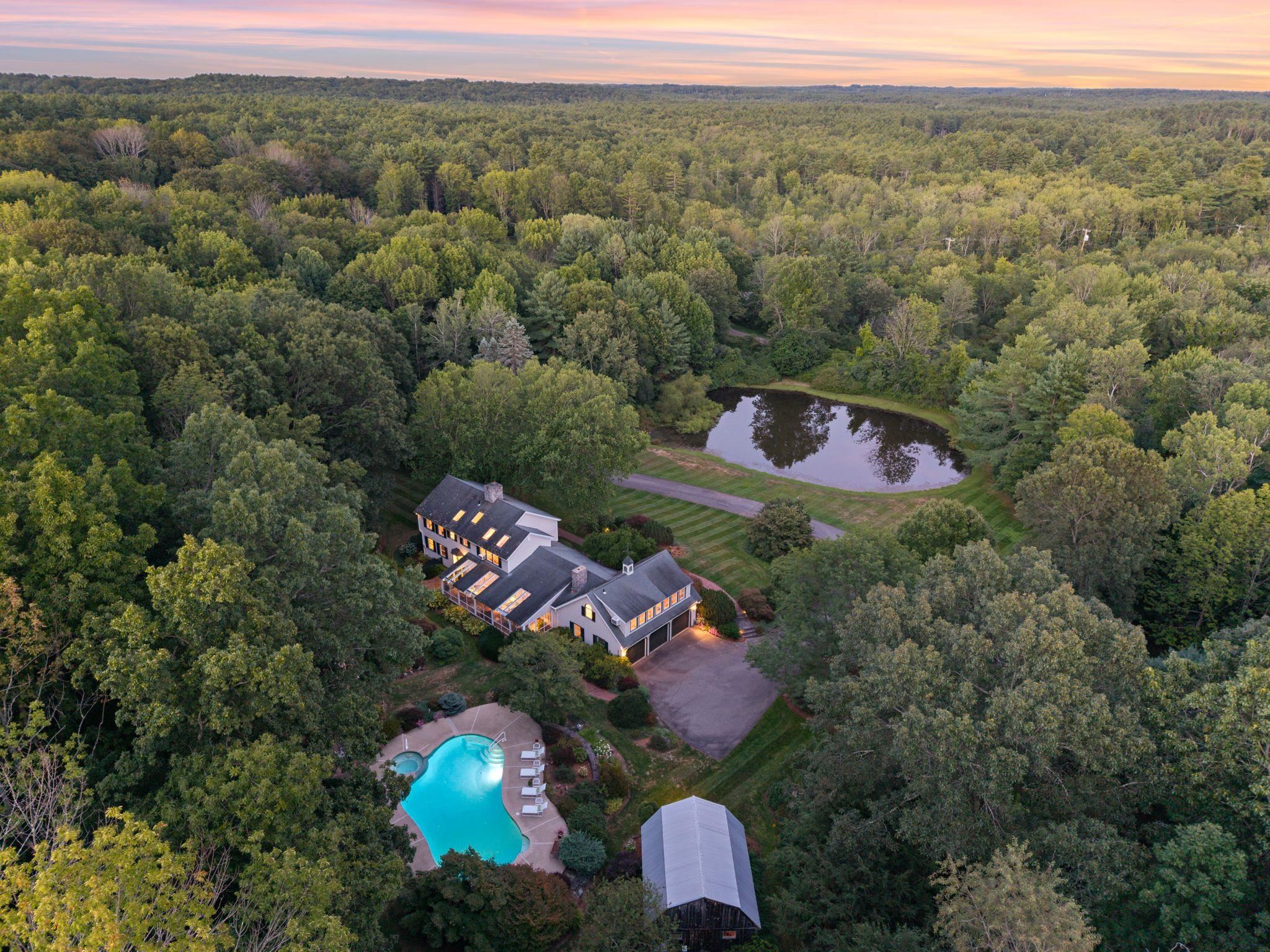 Your opportunity to own this picturesque Hampton Falls estate has arrived. Set on 8 private acres, this exceptional colonial overlooks a tranquil pond & features a quintessential New England barn, a sparkling gunite pool w/ hot tub, & landscaping that evokes a botanical garden setting. At night, thoughtfully designed landscape lighting transforms the grounds, creating a dramatic ambiance & the perfect backdrop for evening gatherings. From the moment you approach along the private driveway, the estate-like presence of this home becomes clear. A gracious brick herringbone porch introduces the refined character & thoughtful design within. Inside, every detail has been carefully considered, with imported tile, custom millwork, built-ins, & hardwood floors throughout. The chef’s kitchen, crafted on site with custom cabinetry & fine finishes, is enhanced by artisan detailing, high-end appliances, & French doors that fill the rooms with natural light and views of the grounds. Upstairs, four well-appointed bedrooms showcase serene views of the property. Above the garage, a spacious bonus room with a private entrance includes custom built-ins, a kitchen, ¾ bath, & large closet—ideal for recreation, extended stays, or guest accommodations. One of the home’s most captivating spaces is the sun drenched oversized screened porch, complete with large skylights & a brick herringbone floor, offering plenty of relaxing & dining enjoyment of the landscape and pool views.  Close to I95 & 101.