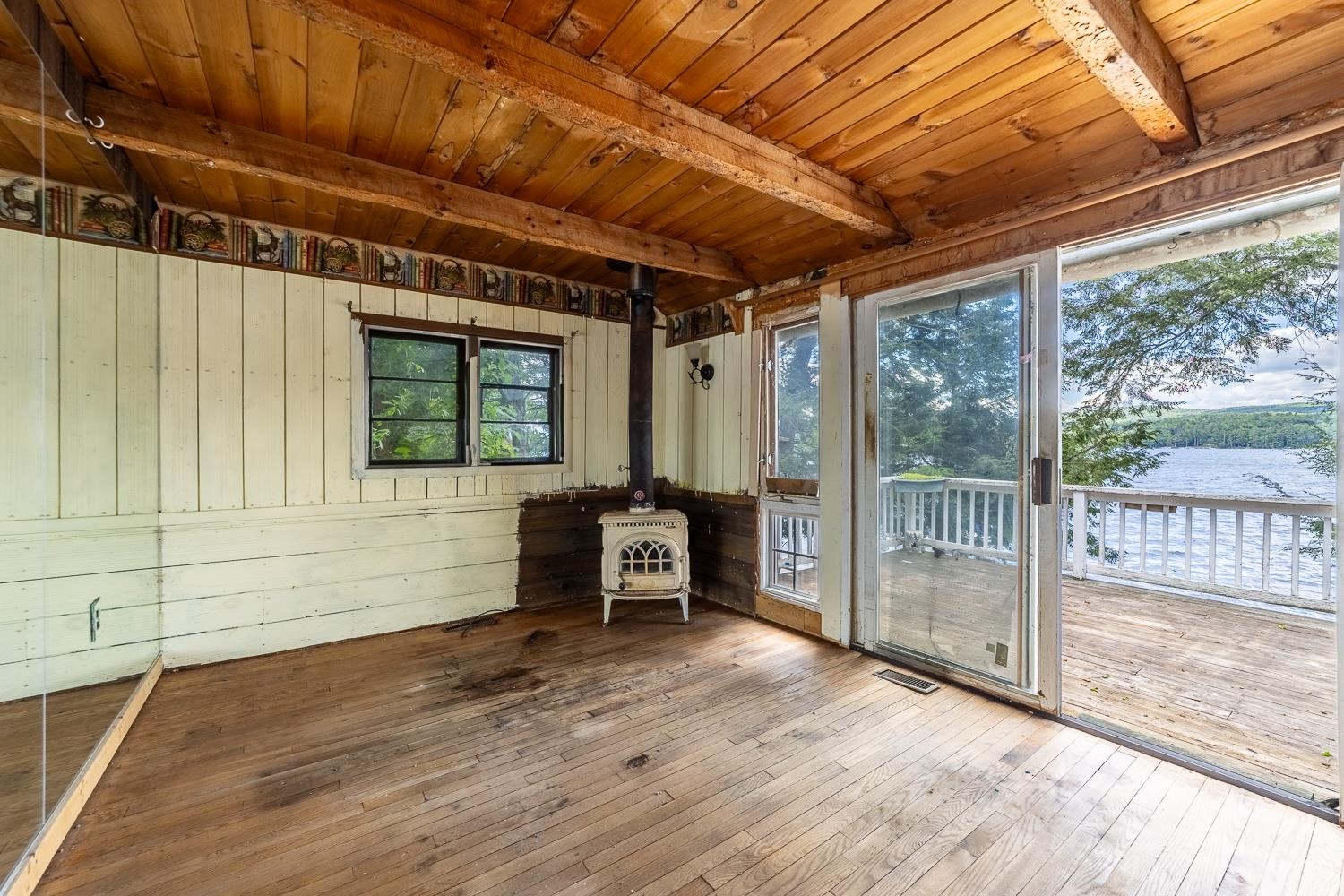 Hardwood-floored living room flows seamlessly to a spacious open deck with sweeping lake views. 25647721