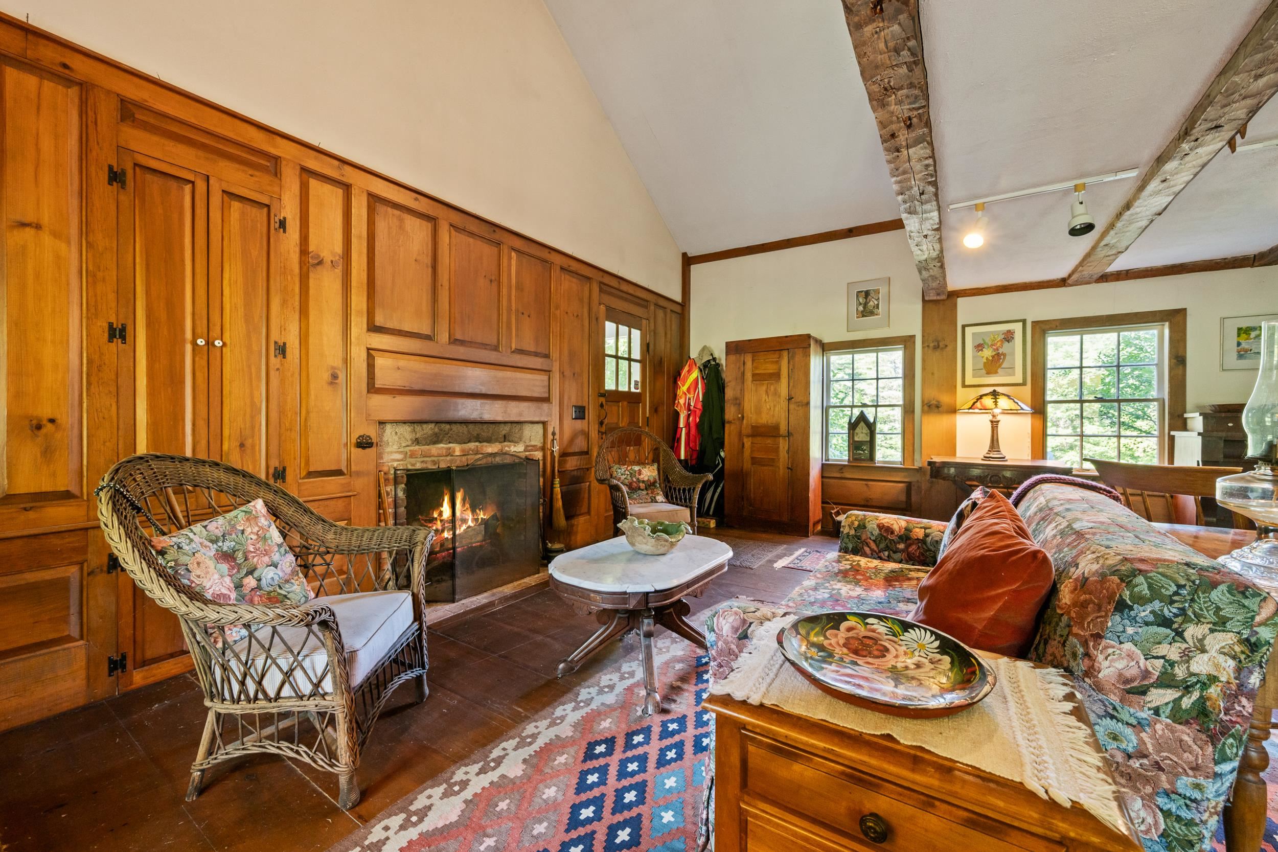 ONE WALL IS A RAISED WOOD PANELED WALL SURROUNDING A LOVELY BRICK FIREPLACE.