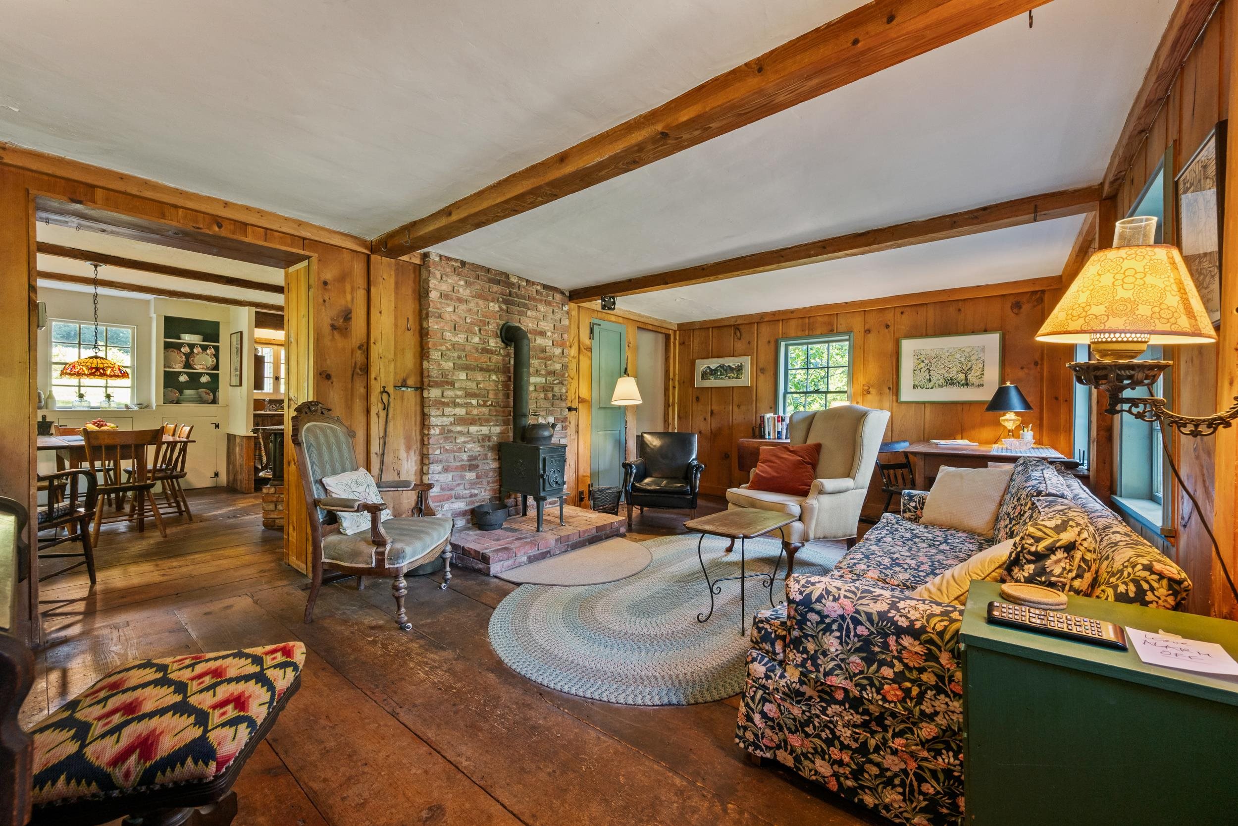 THE LIVING ROOM BOASTS OLD PINE WOOD FLOORS AND A NEW BRICK CHIMNEY WITH A  WOODSTOVE.