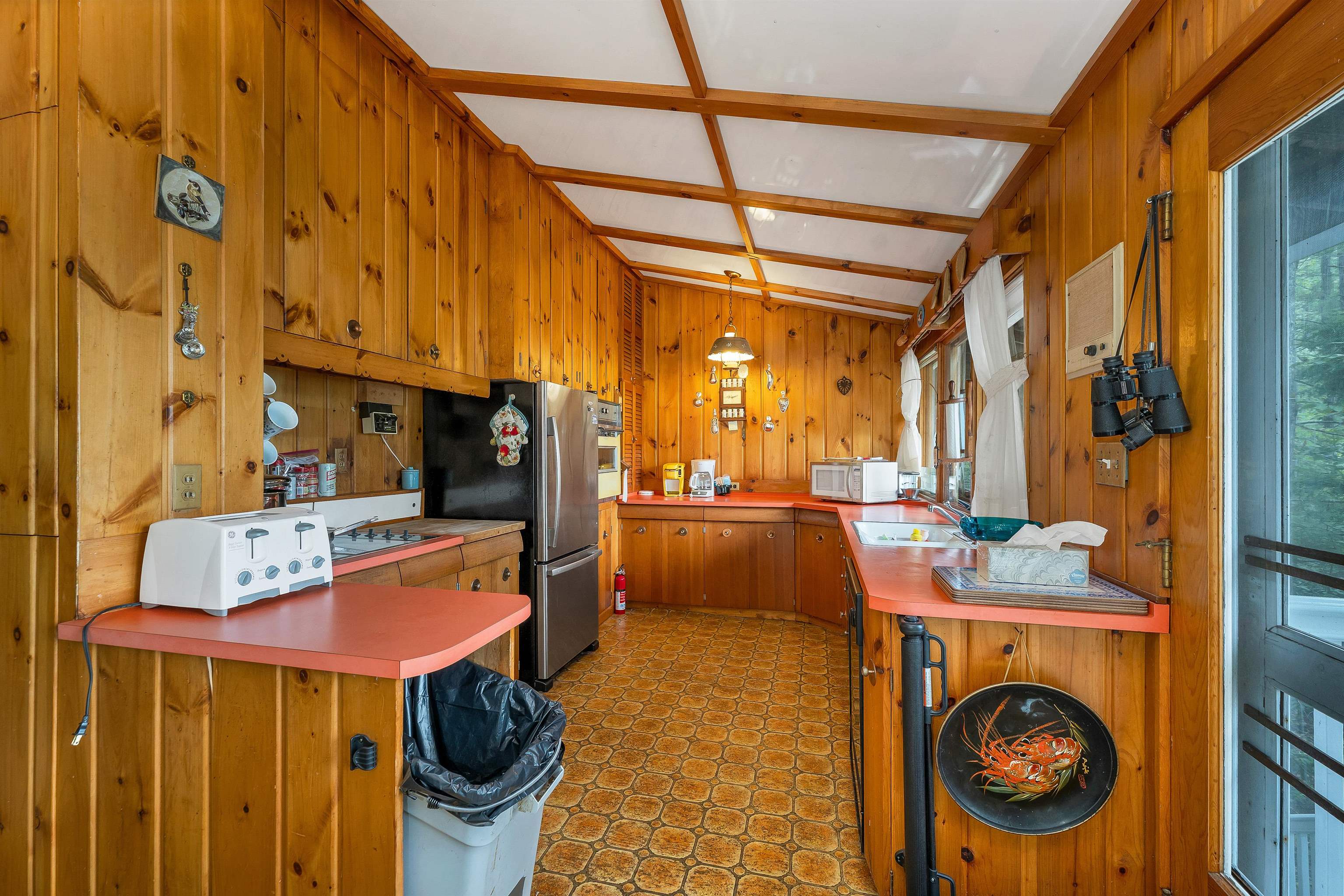 THE KITCHEN FEATURES WOOD CABINETS WITH A NEWER REFRIGERATOR.