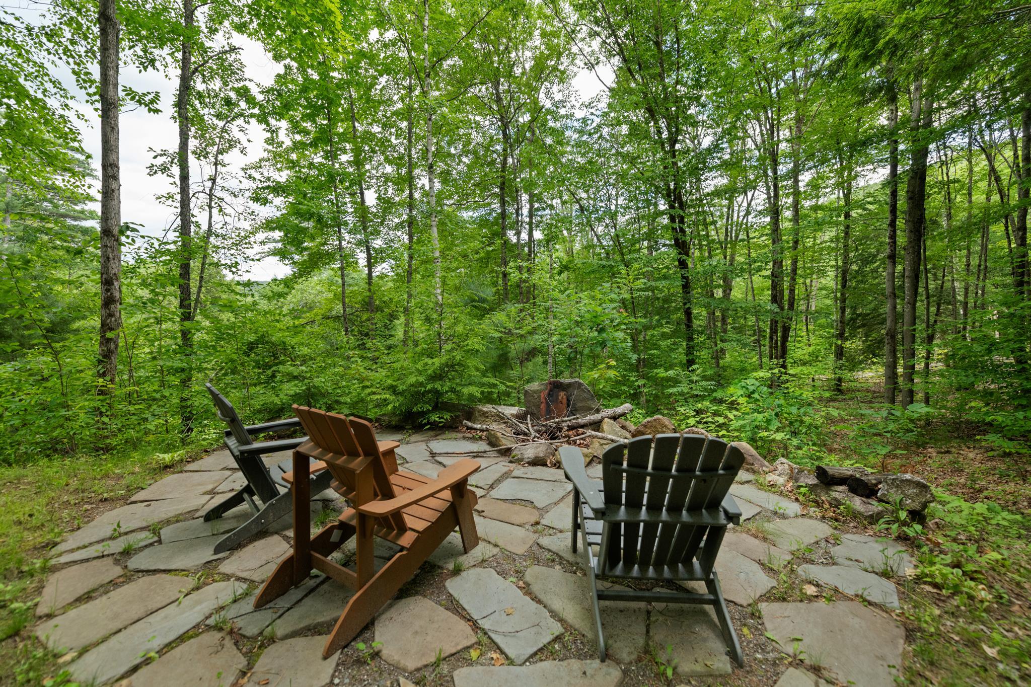A fire pit tucked in the back of the house with a stone patio