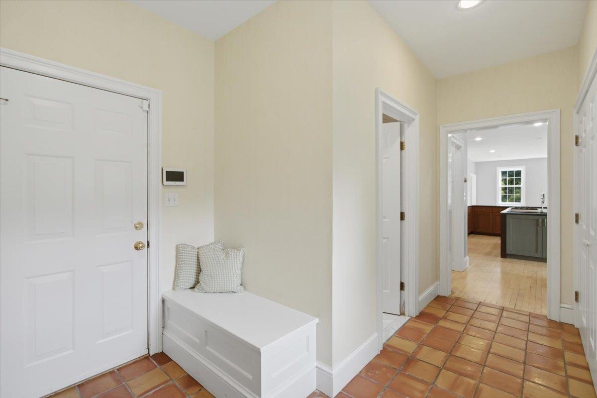 Mud Room with terracotta tile, adjacent to front yard, garage and powder room.