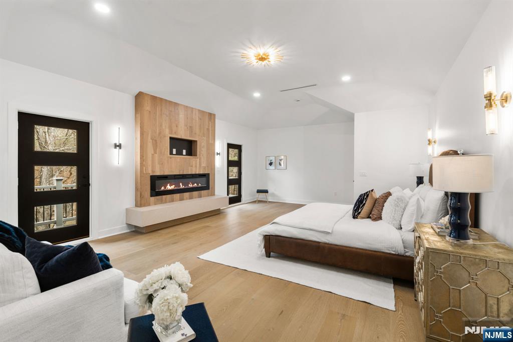The primary suite is a true sanctuary, featuring soaring ceilings, a sleek fireplace, and a private balcony overlooking the surrounding landscape