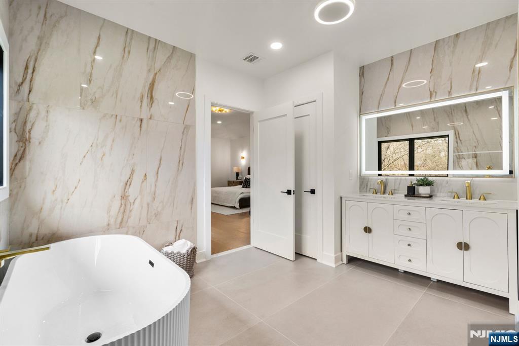 Spa-inspired bath showcases a freestanding soaking tub, dual vanities, and a private water closet